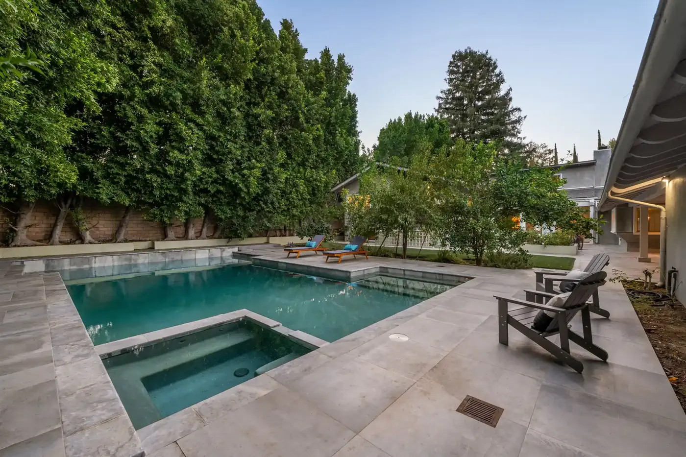 Backyard pool with a green tint to the water beside a stone patio, showing early stage algae growth in a GTA pool