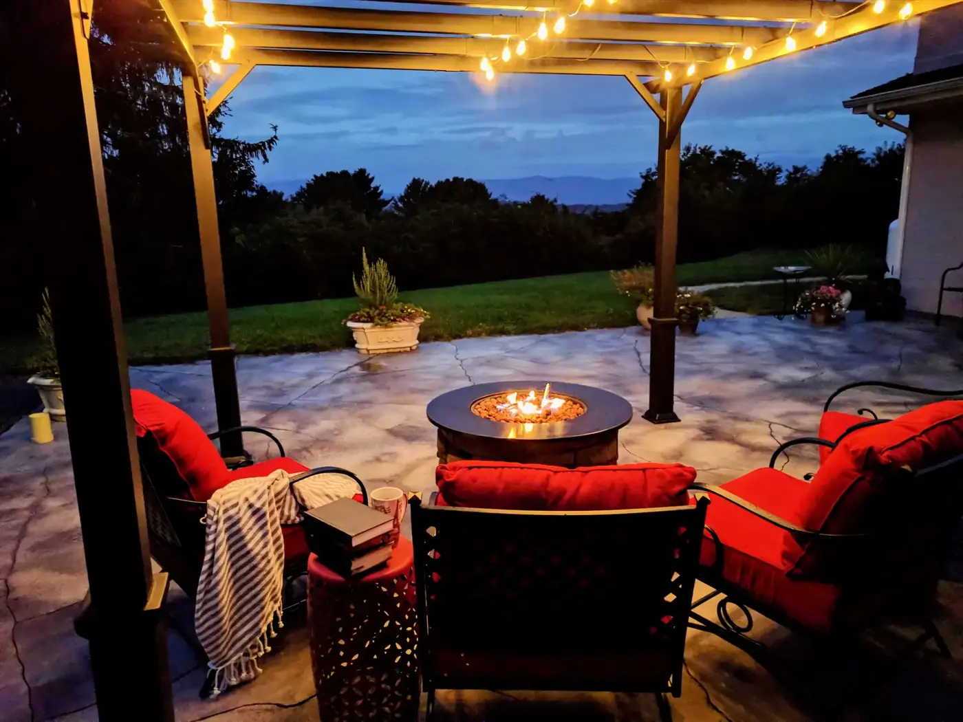 Stamped concrete patio at dusk with pergola, string lights and fire table in a Toronto area backyard