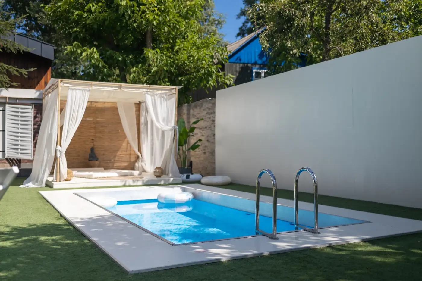 Small backyard pool enclosed by a solid privacy wall and fencing meeting Ontario pool enclosure requirements